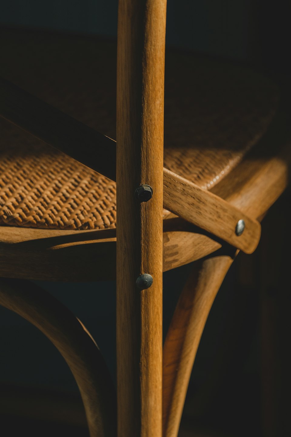 A brown wooden chair with a woven rattan seat.