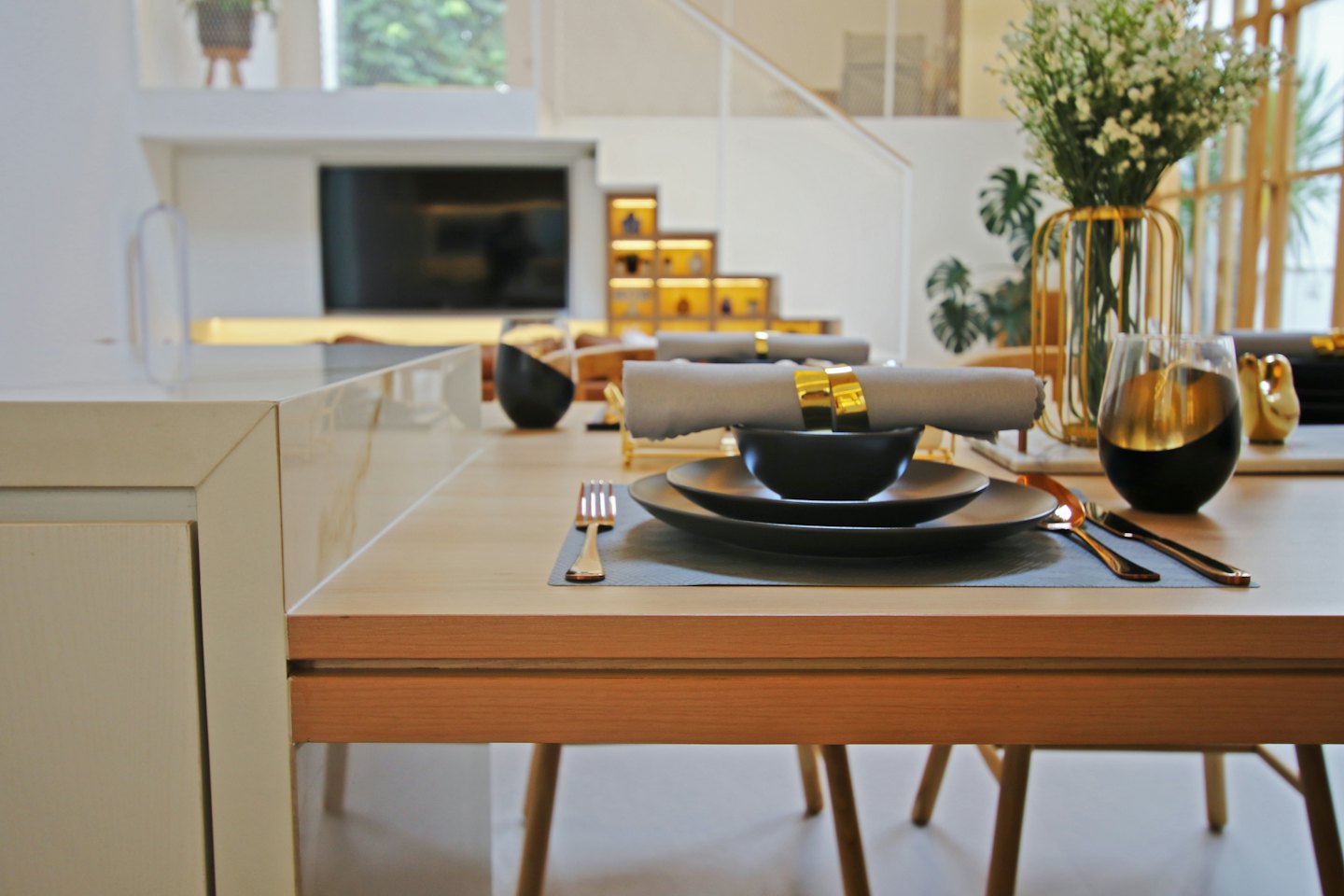 Table settings with plates and gold cutlery in a home.