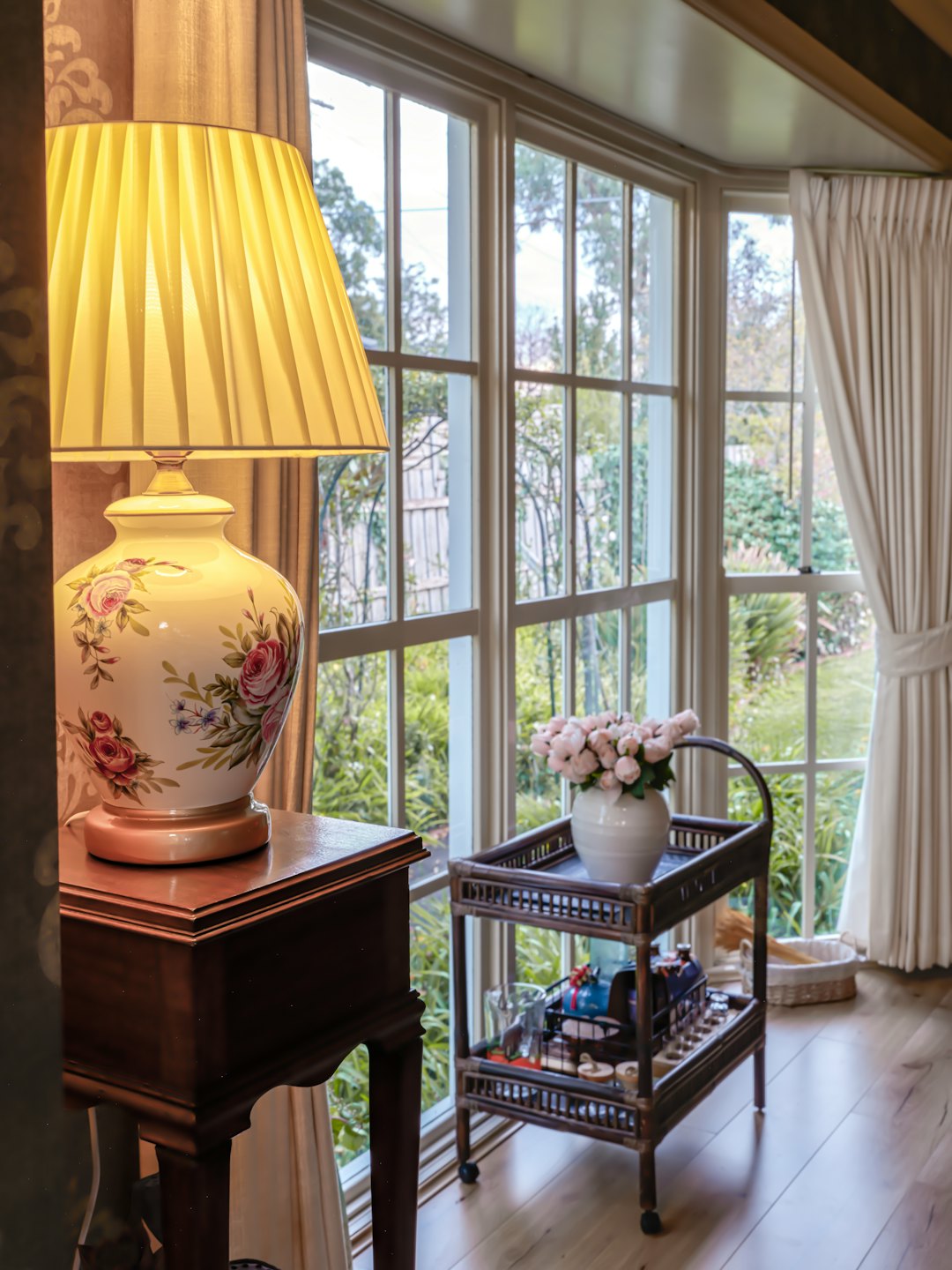 Ceramic lamp and bar cart sit by a sunny window.